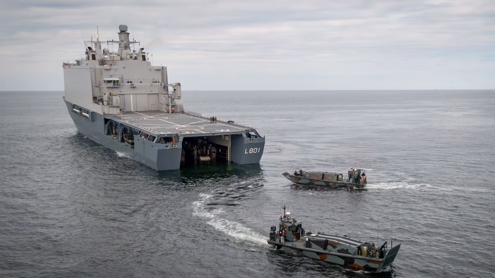 Marineschip op zee met twee kleinere schepen achter het schip.